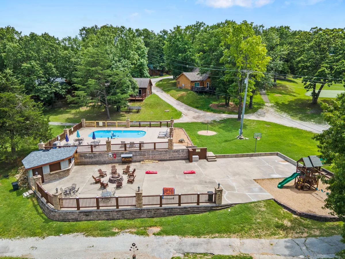 A vibrant view of the resort’s swimming pool, complete with seating, a playground, and a basketball hoop, all surrounded by greenery. The space is active and family-friendly, capturing the lively resort amenities accessible just steps from the deck.