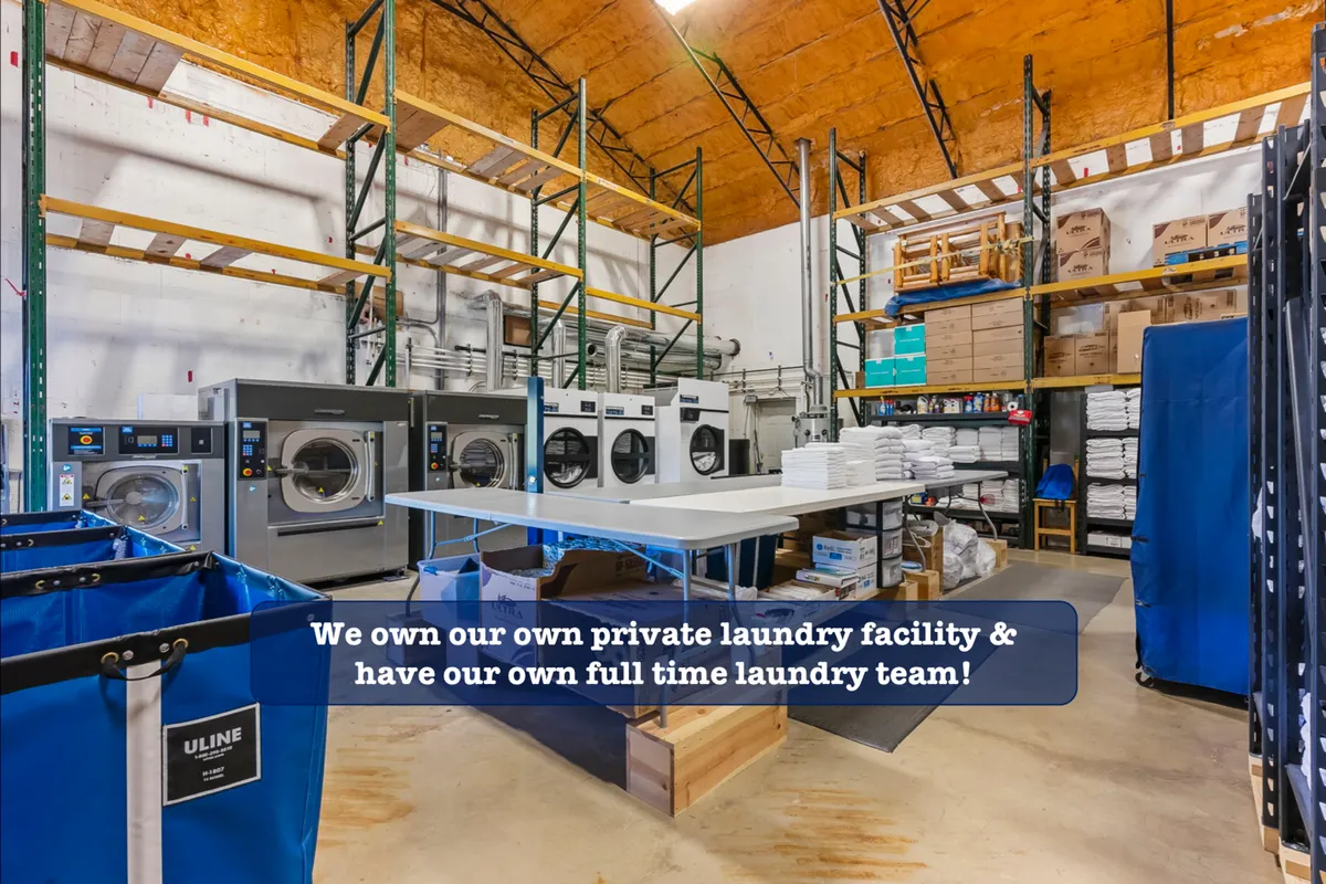 The image captures a commercial laundry facility with industrial washing machines, laundry carts, and shelves stocked with cleaning supplies. The space appears clean, well-organized, and efficient, giving a behind-the-scenes look at the property’s commitment to high standards of cleanliness.