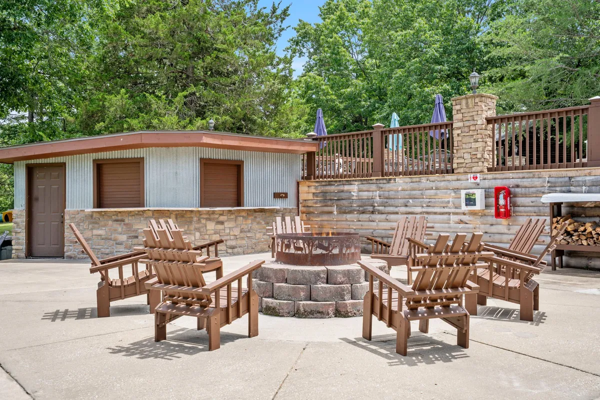 A spacious sand volleyball court surrounded by mature trees and background buildings, ideal for group games and social outdoor gatherings. The setting evokes a lively, communal mood, perfect for evening matches or daytime play.